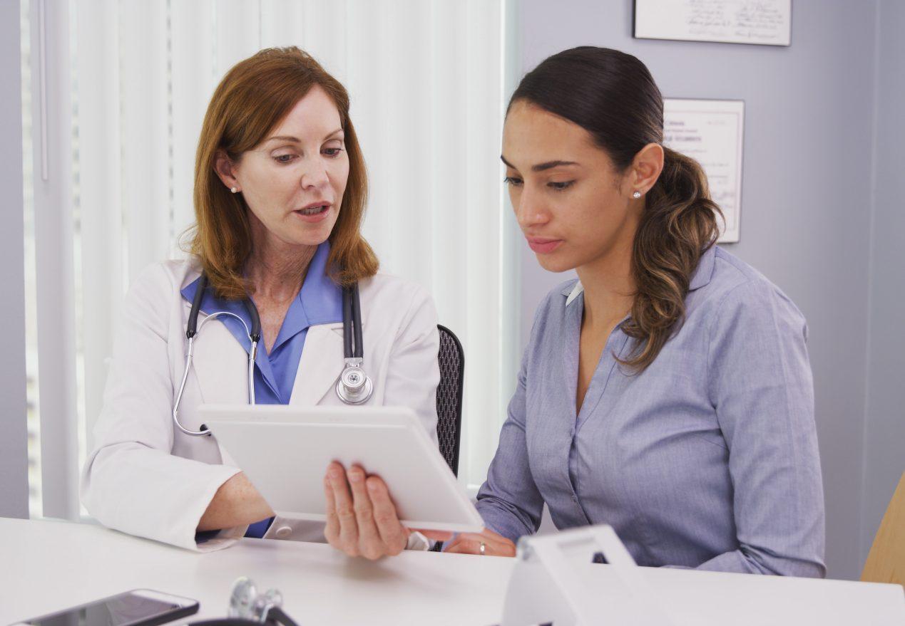 Portrait of beautiful latina patient consulting with doctor on tablet